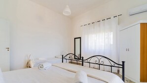 A bedroom with a bed, a wardrobe, a mirror, and a hanging light fixture. - Villetta Della Fonte (Racale)