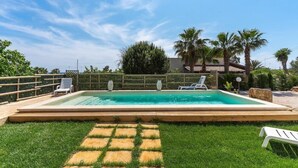A rectangular swimming pool with a wooden deck, surrounded by a wooden fence and palm trees. - Villetta Della Fonte (Racale)
