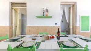 A dining table set with plates, cutlery, and food items, with a bottle of olive oil and a bowl of pasta. - Villetta Della Fonte (Racale)
