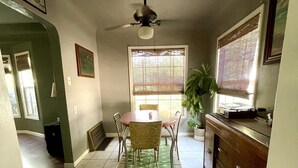 A dining area with a table, chairs, a ceiling fan, and a window with blinds. - Downtown Eclectic Bungalow (Oakdale)