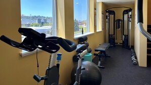 A gym with exercise equipment, large windows, and a view of buildings outside. - Rooftop Hot Tub in Downtown Walnut Creek (Walnut Creek)