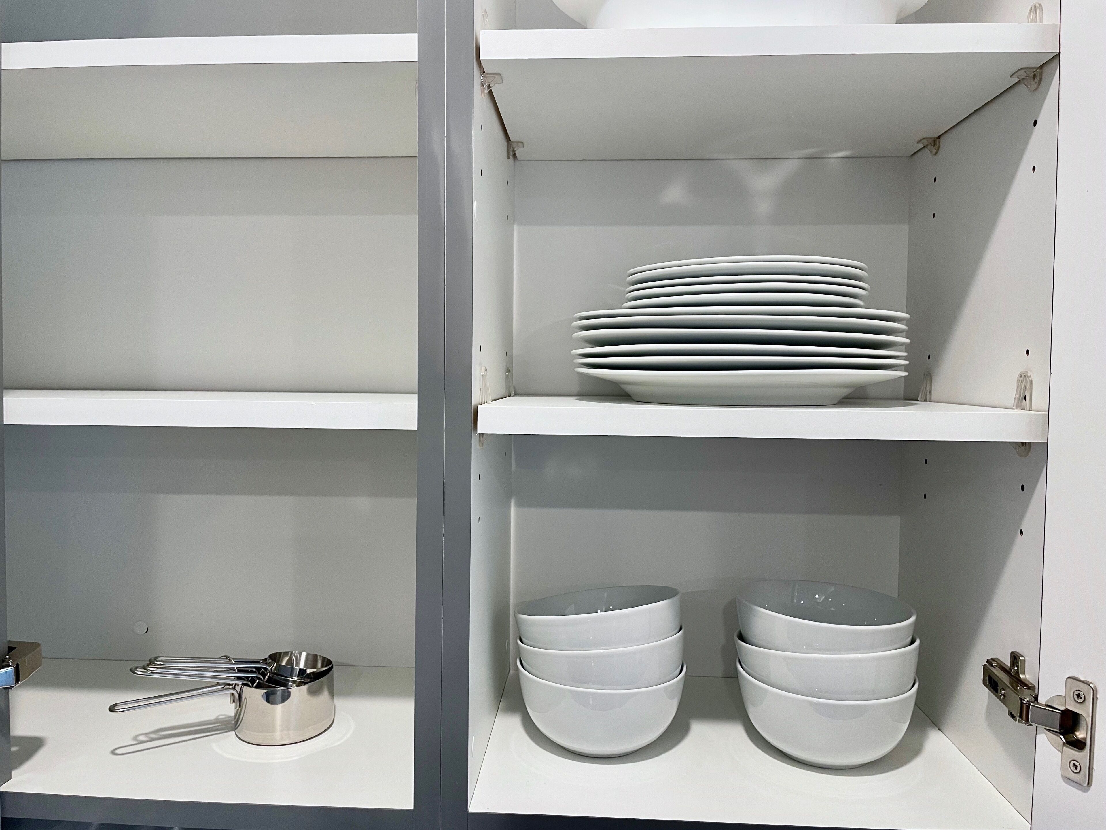 A kitchen with white shelves, a sink, and a stainless steel utensil holder.