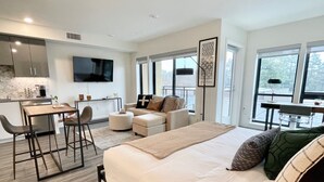 A modern hotel room with a large bed, a sofa, a dining area, and a kitchen. - Rooftop Hot Tub in Downtown Walnut Creek (Walnut Creek)