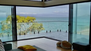 Una sala de estar moderna con un amplio balcón de vidrio con vistas al mar.
