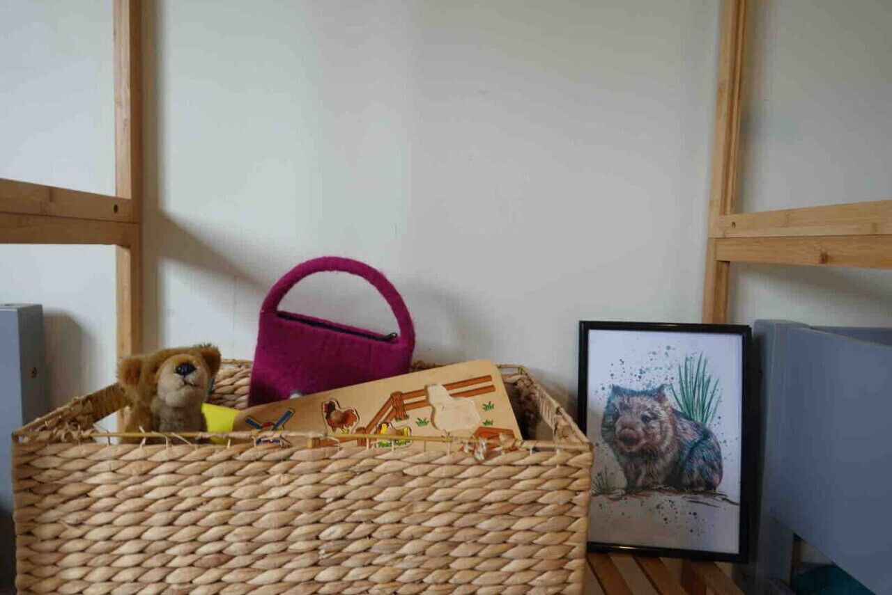 A wicker basket with a pink handle, a framed picture of a guinea pig, and a stuffed animal.