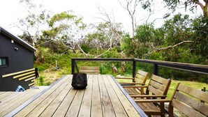 A wooden deck with a table and benches, surrounded by greenery and a building. - Beachside Family Surf Retreat (Carlton)