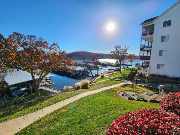 A residential area with a pathway, a dock, and a building with balconies overlooking a body of water.