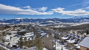 Una zona residencial con casas, cielo despejado y montañas nevadas al fondo.