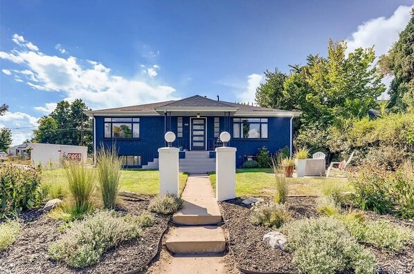 A two-story house with a front porch, a small garden, and a clear sky. - Cozy central home in Chaffee Park near Highlands (Denver)