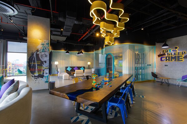 A modern lounge area with a long wooden table, blue chairs, and a colorful wall mural. - Tru by Hilton Lang Son City Centre (Lang Son)