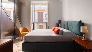 Un dormitorio con una cama, una silla, una mesita de noche y vistas a un balcón.