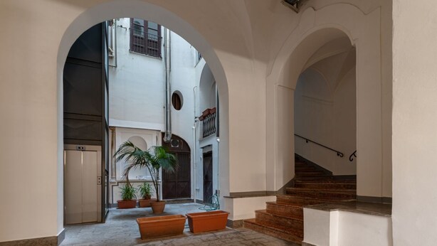 Un interior espacioso con un patio central, una escalera y una puerta que da a un ascensor.
