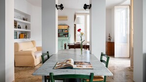 Un comedor con una mesa de mármol, sillas verdes y un libro abierto sobre la mesa.