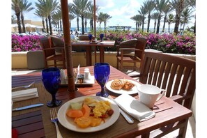 Enjoy a leisurely breakfast with a view of the ocean and palm trees from this outdoor dining area.