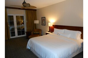 Relax in this serene space with a large bed, ceiling fan, and comfortable chair.