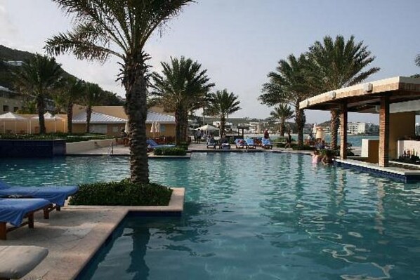 Relax by the pool surrounded by palm trees and lounge chairs.