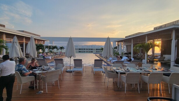 A deck with outdoor seating, umbrellas, and a view of the sea. - Stunning Loft Grand Luxxe (Nuevo Vallarta)