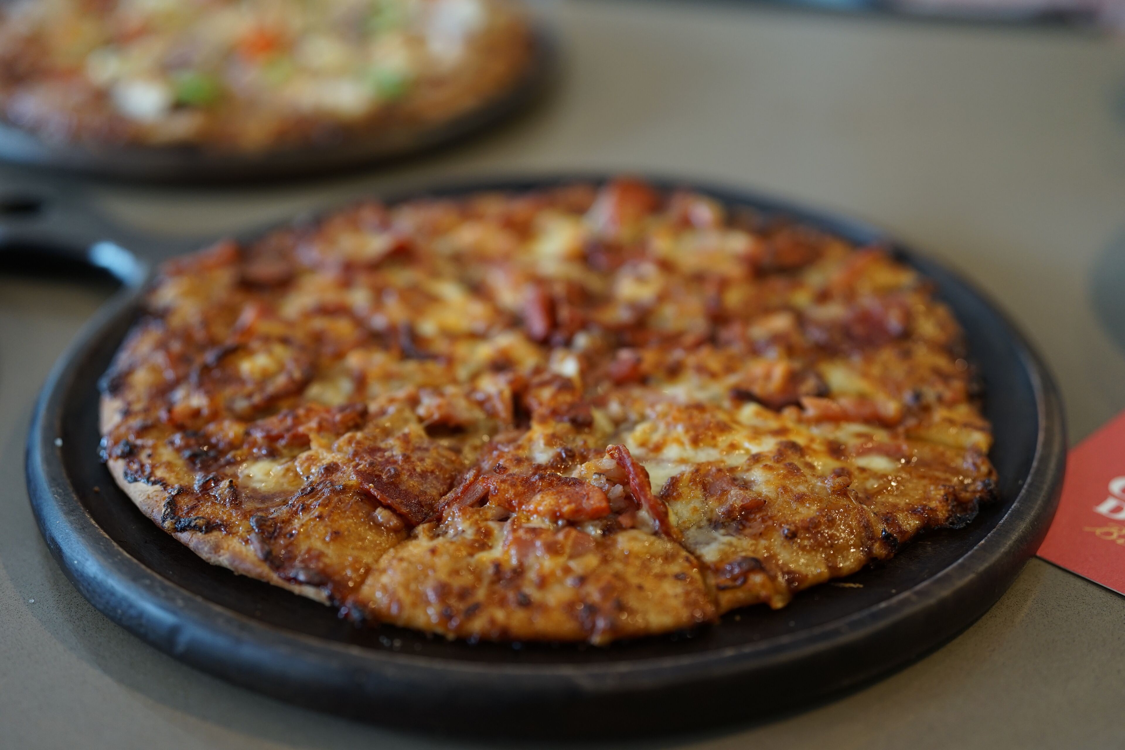 Une pizza avec des ingrédients bien visibles, servie sur une assiette noire.