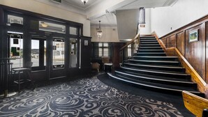 A grand staircase with a carpeted floor leading to an upper level. - Hotel Queanbeyan Canberra (Queanbeyan)