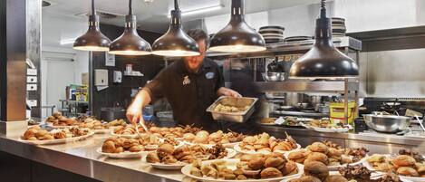 A buffet setup with various food items and a person serving.