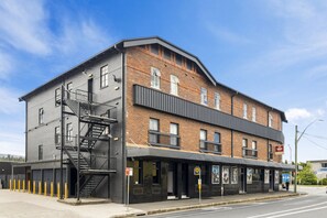 A two-story building with a fire escape, a covered entrance, and a sign indicating a restaurant. - Hotel Queanbeyan Canberra (Queanbeyan)