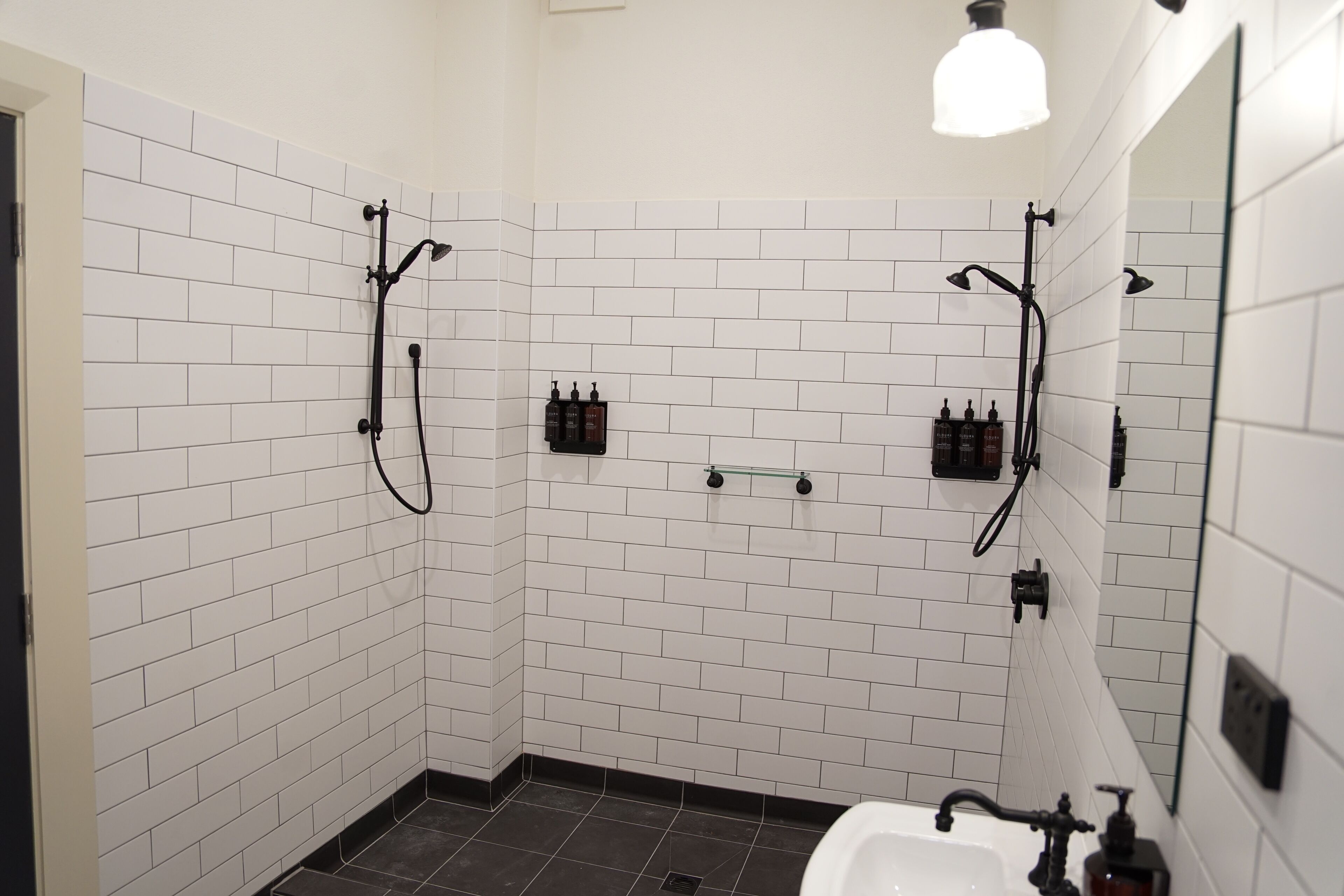 A modern bathroom with white subway tiles, a black bathtub, and a handheld showerhead.