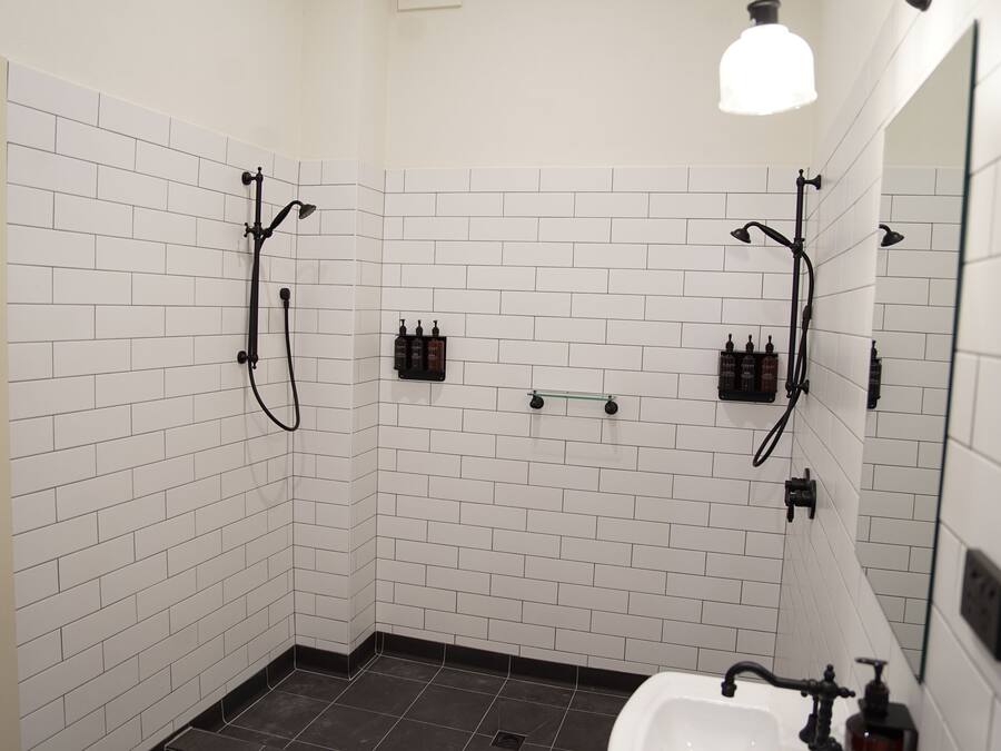 A modern bathroom with white subway tiles, a black bathtub, and a handheld showerhead.