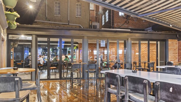An indoor dining area with wooden flooring, metal tables, and chairs. - Hotel Queanbeyan Canberra (Queanbeyan)