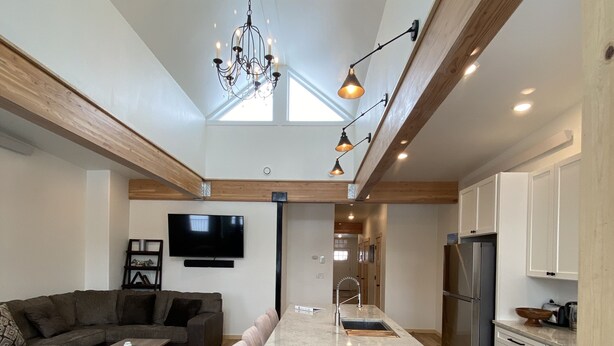 A modern open-plan living and kitchen area with a central island, wooden beams, and a chandelier. - The White House- Suite B Upstairs (Silverton)