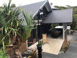 A modern house with a covered patio, outdoor furniture, and large green plants. - BESPOKE VILLA WITH A DOPE BEACH VIBE (boomerang beach)