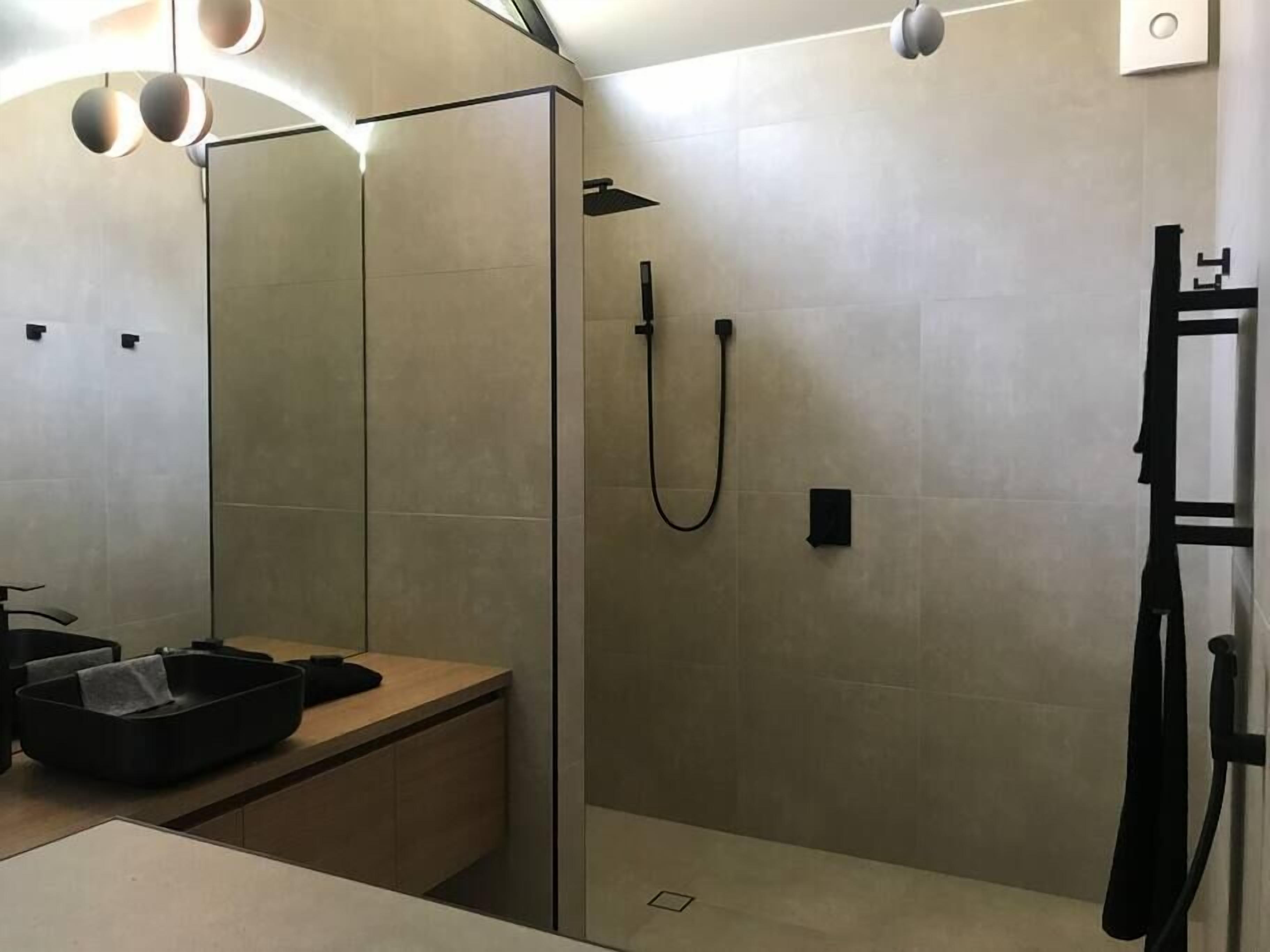 A modern bathroom with a shower, a sink, and a mirror.