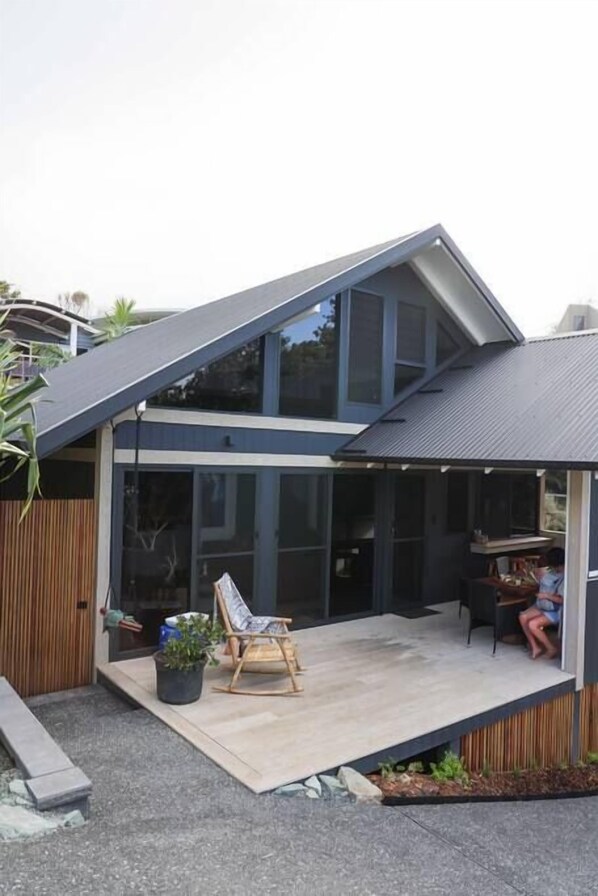 A modern house with a large glass door leading to a covered patio area.