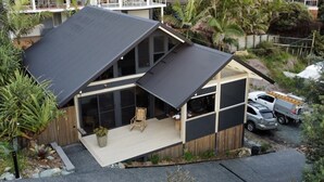 A modern house with a large deck, a carport, and a garage.