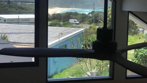 A room with large windows overlooking a beach and a hilly landscape.