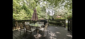 Relax on the deck surrounded by lush greenery, with a glass-top table and four comfortable chairs.