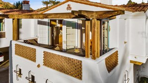 A white building with a balcony, wooden beams, and a tiled roof. - SV111 Contemporary 1 Bedroom Spa Villa (La Quinta)