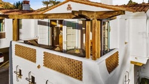 A white building with a balcony, wooden beams, and a tiled roof.