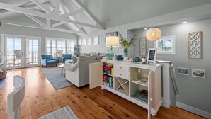 A spacious living room with a large window, a white sofa, a coffee table, and a bookshelf. - Neuse Village #3 - Check out the amazing views! (Arapahoe)