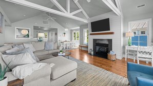 A spacious living room with a fireplace, a ceiling fan, and a television mounted on the wall. - Neuse Village #3 - Check out the amazing views! (Arapahoe)