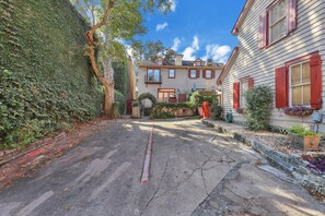 Une rue résidentielle bordée de maisons, avec une allée d’accès ombragée par des arbres et un ciel dégagé.