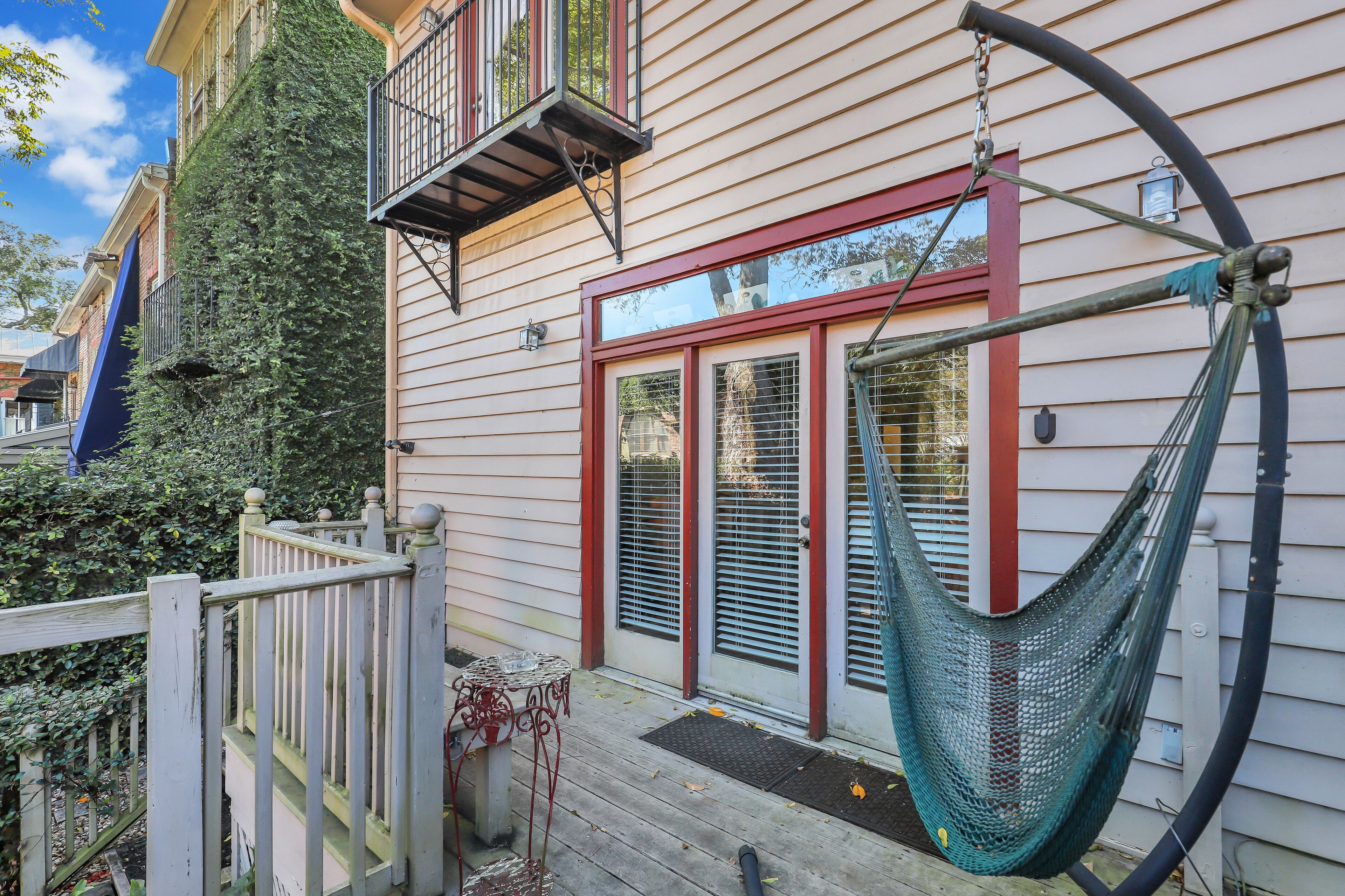A house with a hammock on the porch, a wooden deck, and a metal railing.