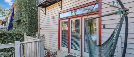 A house with a hammock on the porch, a wooden deck, and a metal railing.