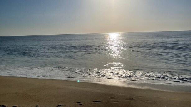 Una playa con el sol reflejándose en el agua.