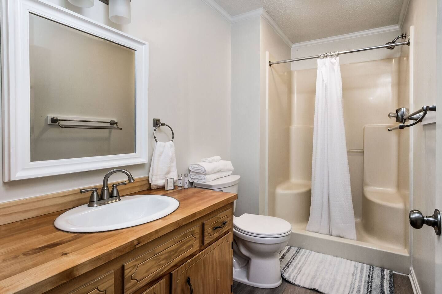 A bathroom with a wooden vanity, white sink, and a glass shower enclosure.