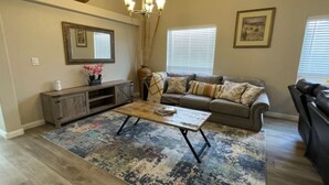 A living room with a sofa, a coffee table, a rug, a cabinet, and a chandelier. - Vegas Vacation Home ... Close to The STRIP (North Las Vegas)