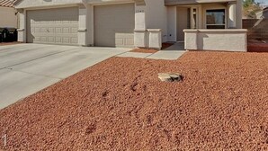 A single-story house with a garage, a front porch, and a red gravel driveway. - Vegas Vacation Home ... Close to The STRIP (North Las Vegas)