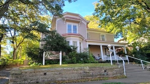 A two-story house with a porch and a stone wall in front.