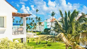 Een resort met een wit gebouw, een overdekt terras en palmbomen.