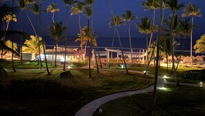 Een resort met palmbomen, een pad en een gebouw met verlichting.