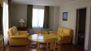 Una habitación con un sofá amarillo, una mesa redonda de madera y una lámpara.